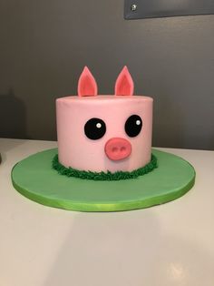 a pink pig cake sitting on top of a green plate