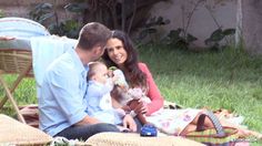 a man and woman are sitting on the grass with their baby