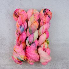 several skeins of pink and yellow yarn on a white surface with grey background