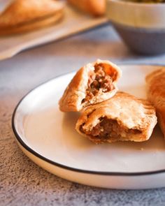 two pastries on a plate next to a bowl of soup and some other food