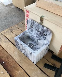 a marble sink sitting on top of a wooden pallet next to a box and other items