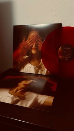 a red vinyl album sitting on top of a wooden table