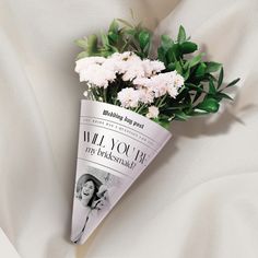 a paper cone with flowers in it on a white sheet