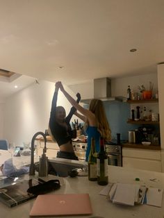 two women are dancing in the kitchen together