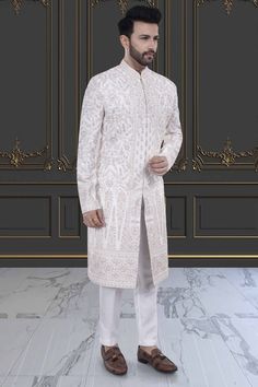 This impeccable sherwani, adorned with luxurious stones and intricate embroidery, exudes sophistication and elegance. Perfect for the stylish groom, it is a timeless masterpiece that will make a lasting impression. Indulge in the opulence and elevate your wedding day look with this R14-S71 sherwani. Wedding Sherwani With Chikankari Embroidery In Traditional Fit, Elegant Traditional Fit Sherwani For Festive Occasions, White Traditional Sherwani, Elegant White Kurta With Traditional Fit, White Elegant Kurta With Traditional Fit, Embroidered Traditional Fit Sherwani For Wedding, Luxury Embroidered Sherwani For Formal Occasions, Elegant Traditional Wear With Naqshi, Elegant Traditional Wear With Naqshi Drape