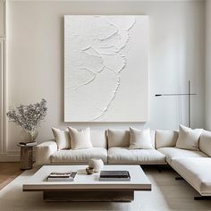 a living room filled with white furniture and a large painting on the wall above it