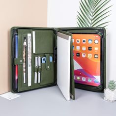 an open ipad case sitting on top of a table next to a potted plant