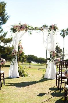 an outdoor wedding setup with white drapes and pink flowers