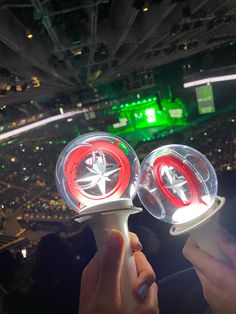 two people are holding up some lights in the middle of a stadium area at night