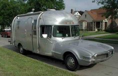 an airstream is parked on the side of the road in front of some houses