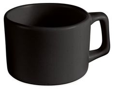 a black coffee cup sitting on top of a white table