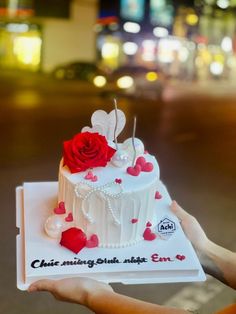 a person holding a cake with red roses on it