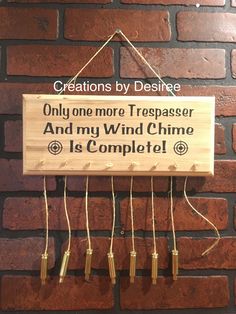 a wooden sign hanging from the side of a brick wall that says, creations by designe only one more trespasser and my wind chime is complete