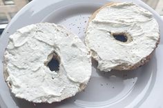 two bagels with white frosting sitting on a plate next to a glass window