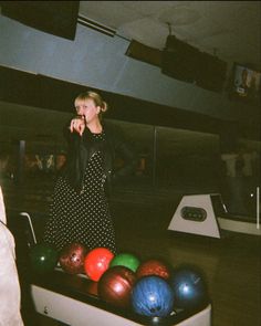 a woman standing in front of bowling balls