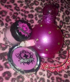 three different types of perfumes on a leopard print tablecloth, one is pink and the other is purple