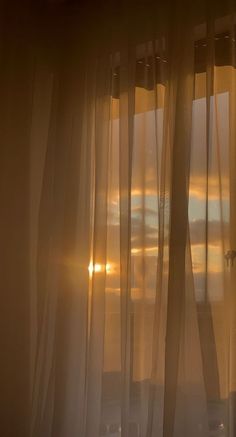 the sun is shining through sheer curtains