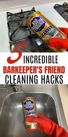 a person in red rubber gloves is cleaning a metal sink with a bottle of soap