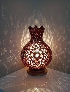 a decorative lamp sitting on top of a white table next to a shadow cast wall