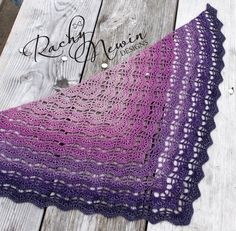 two crocheted shawls sitting on top of a wooden table