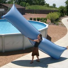 a woman is holding an inflatable object over her head while standing next to a swimming pool