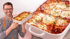 a man is holding up a casserole dish with cheese and sauce on it