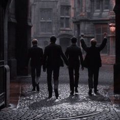 four men walking in the rain holding hands