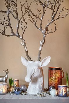 a white deer head sitting on top of a table next to some candles and trees