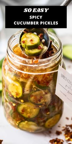 a jar filled with pickles sitting on top of a table next to some spices