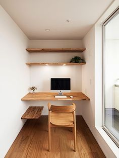 a wooden desk sitting next to a window on top of a hard wood floored floor