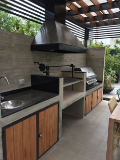 an outdoor kitchen with wood cabinets and stainless steel stove top hood over the sink area