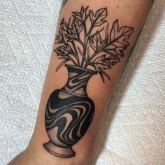 a black and white vase with leaves in it on someone's leg by the bed