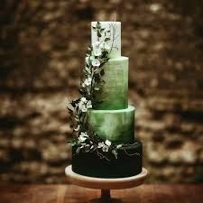 a three tiered green cake with white flowers on the top and bottom, sitting on a wooden table