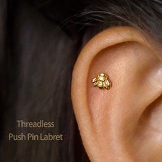 a close up of a person's ear with a small gold bee on it