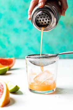 a person pours orange juice into a glass filled with watermelon and lime