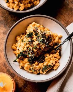 two bowls filled with macaroni and cheese on top of a wooden table