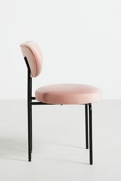 a pink chair sitting on top of a white floor next to a black metal frame