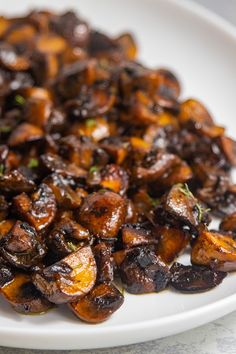 a white plate topped with cooked mushrooms on top of a table