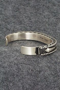 This sterling silver bracelet was made by Navajo silversmith Leander Tahe. The inside is signed L. Tahe and stamped sterling.Size: 5 3/4" (will fit up to a 7 1/8" wrist)Gap: 1 3/8"Width: 3/8"Free shipping on all orders! We ship with USPS and always include tracking. All orders ship within a day of payment.Returns are accepted up to 30 days after you receive your order. Just send us a message. Our shop offers cash back or store credit. The item must be returned in new condition. Southwestern Sterling Silver Polished Bangle Bracelet, Sterling Silver Southwestern Bracelet With Polished Finish, Southwestern Sterling Silver Bangle With Polished Finish, Southwestern Polished Sterling Silver Bangle, Oxidized Sterling Silver Southwestern Bracelet, Oxidized Finish Southwestern Sterling Silver Bracelet, Sterling Silver Bracelet, Native American Jewelry, Free Jewelry