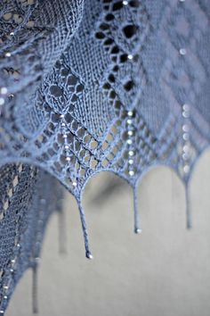 a close up view of a crocheted shawl with drops of water on it