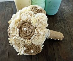 a bridal bouquet sitting on top of a wooden table next to two mason jars