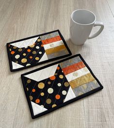 two coasters with different designs on them next to a coffee cup and saucer