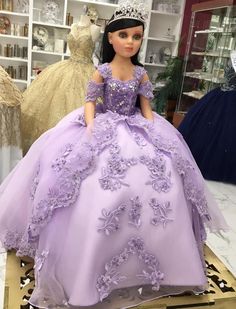 a doll dressed in a purple dress and tiara sitting on top of a table