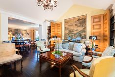 a living room filled with furniture and a chandelier hanging from the ceiling over a wooden floor