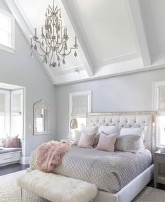 a bed room with a neatly made bed and a chandelier hanging from the ceiling