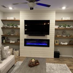 a living room with a couch, fireplace and television on the wall in front of it