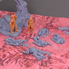 some plastic figurines are laying on a pink table cloth with an arch in the background