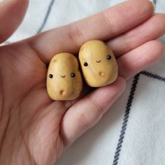 two small wooden toys are in the palm of someone's hand, with eyes drawn on them