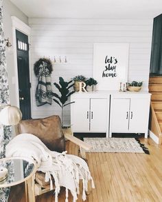 a living room with white walls and wood flooring is pictured in this image, there are plants on the wall