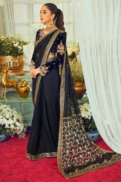 Embroidered Black Velvet Saree Pakistani Wedding Dresses comes in a Premium Black velvet blouse featuring antique and gold embroidery details enhanced with red Resham rosettes, the sleeves of the blouse are enhanced with dangling pearls, the back of the sari is adorned with handcrafted tassels, the net embroidered sari is enhanced with light-catching crystals finished with sequins. The pallu of the sari is enhanced with sequins and zardozi motifs. Black Velvet Saree: Classic and eye-catching! Ma Velvet Long Sleeve Traditional Wear For Weddings, Velvet Traditional Wear With Pallu For Wedding, Wedding Velvet Traditional Wear With Pallu, Velvet Saree With Resham Embroidery For Reception, Festive Saree With Intricate Embroidery And Long Sleeves, Velvet Saree For Wedding, Velvet Saree With Pallu For Wedding, Traditional Velvet Saree For Festivals, Traditional Embellished Saree For Reception